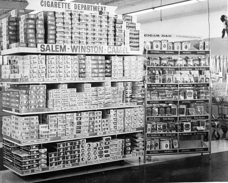A display of tobacco cigarettes in a grocery store. Signs read "Cigarette Department" and Salem-Winston-Camel."