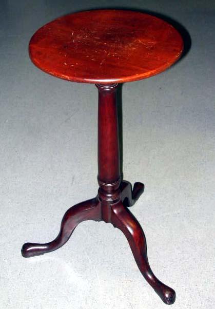 Small round table with a red tinted wood.