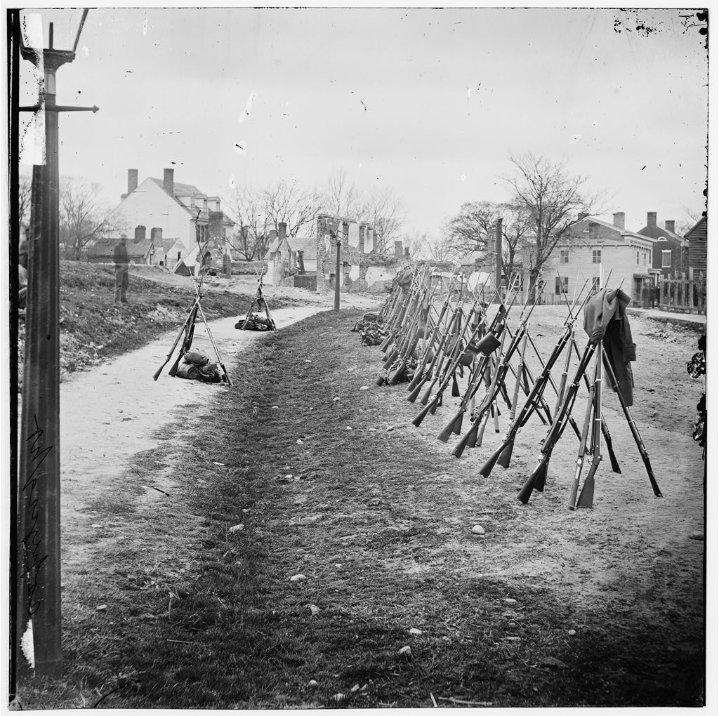 Image of a row of Union rifles stand stacked against each other in Petersburg, Virginia.