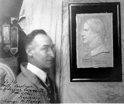 George H. Honig, at left, with bust of Richard Henderson. He is smiling. 