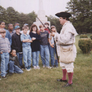 Image of re-enactor with visitors at the Alamance Battleground State Historic Site.