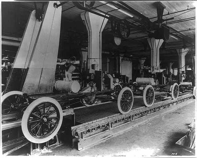Photograph of a Ford Model T assembly line in 1913. The factory was located in Highland Park, MI, near Detroit. This image comes from the collections of the Library of Congress.