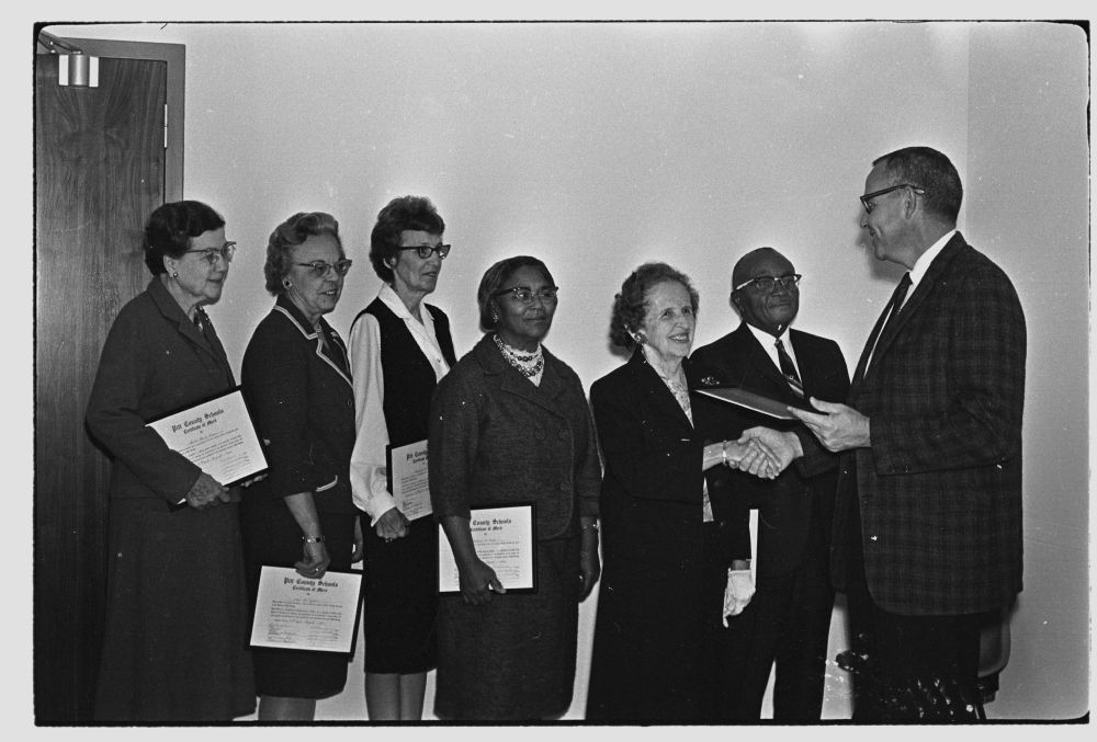 Photograph of Pitt County Schools Superintendent Arthur S. &quot;Ott&quot; Alford (far right) presenting certificates to school system faculty and staff. This photograph is from the Daily Reflector Image Collection at ECU and is for use only in research, teaching, and private study. 