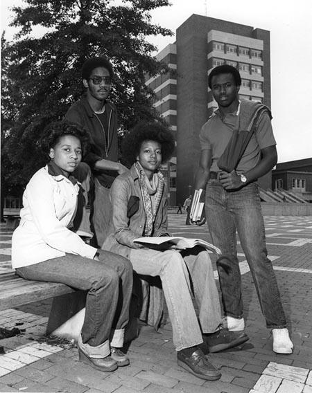 Four African American students sit outside of North Carolina State University's D.H. Hill Library in 1970.