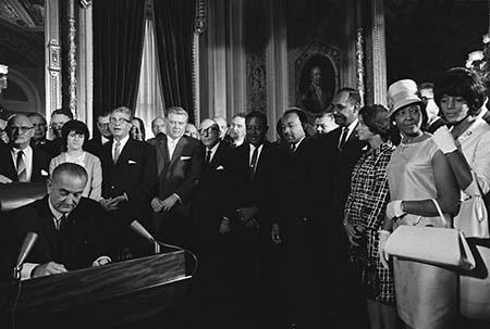 In this photo President Lyndon B. Johnson signs the Voting Rights Act as Martin Luther King Jr. and other civil rights leaders look on, August 6, 1965, United States Capitol, Washington, D.C.