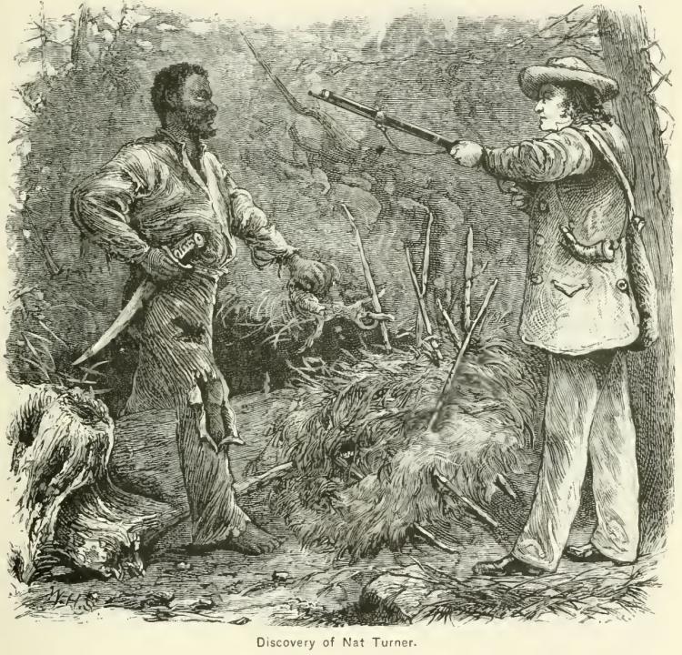 Nat, left. A blade is at his waste and his clothes are tattered. Another man, right, is pointing a gun at him.
