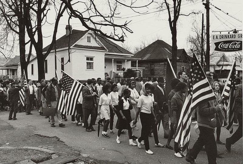 Participants, some carrying American flags, marching in the civil rights march, 1965
