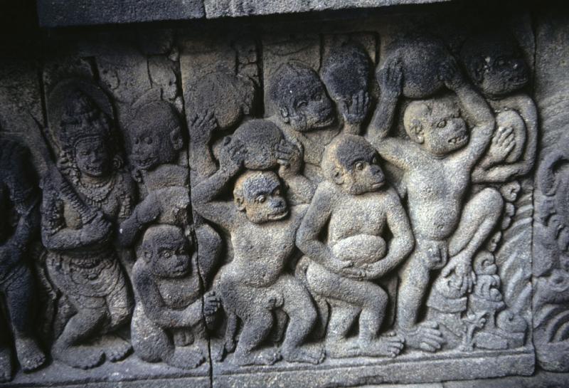 A stone relief depicts monkeys carrying stones overhead. 
