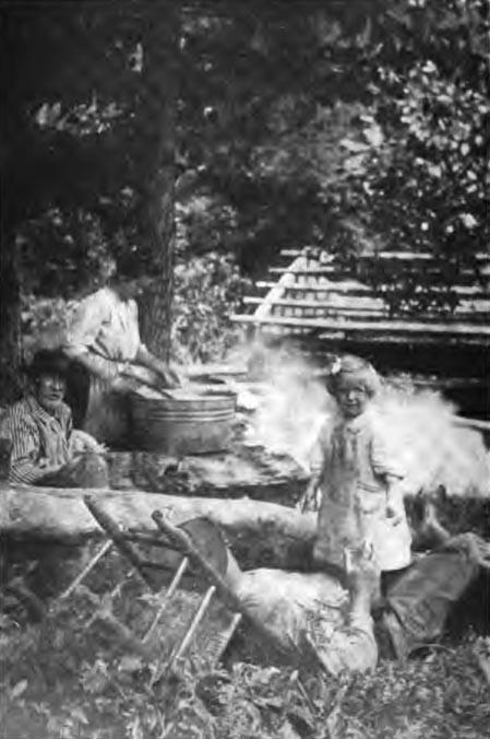 A picture of three adults and one child. A man rests while the child plays near him. Another man sits beside the woman while she cooks or cleans.