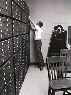 Don Lennon, Coordinator of Special Collections at ECU, reaching for materials in the library archives, circa 1970-1980. Image from Digital Collections, J.Y. Joyner Library, East Carolina University.