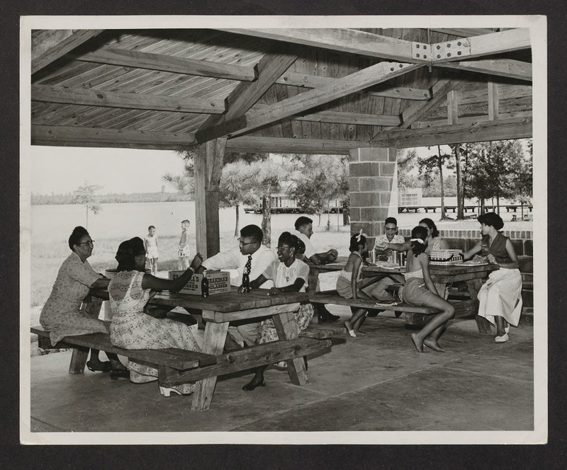 A family picnicking under a picnic shelter, circa 1950. Jones Lake State Park opened in the summer of 1939 as the first state park for African Americans, and achieved immediate popularity. In later years the park, like all other North Carolina State Parks, became fully integrated.