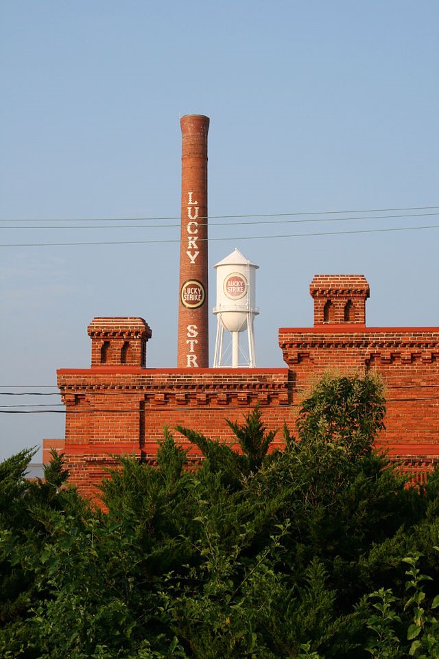 Ildar Sagdejev . “Lucky Strike chimney and water tower of the American Tobacco Historic District seen from the railroad in Durham, North Carolina.”  From Wikimedia Commons, used under the GNU Free Documentation License.