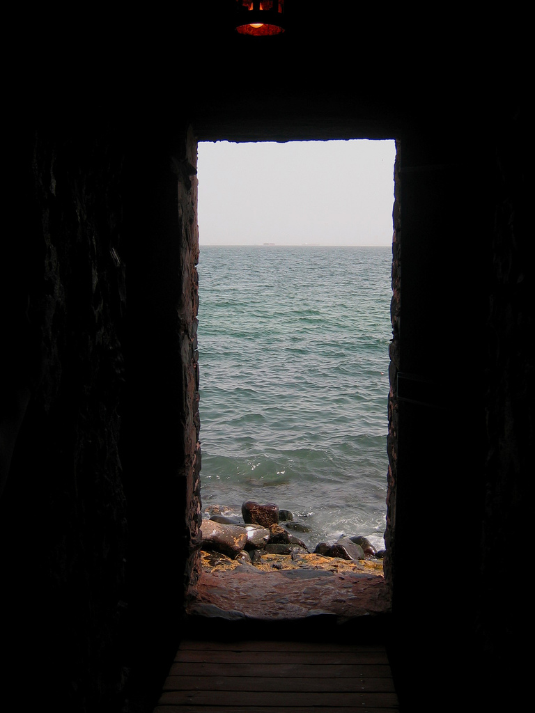 A small carved exit in a stone wall looks out into the ocean.
