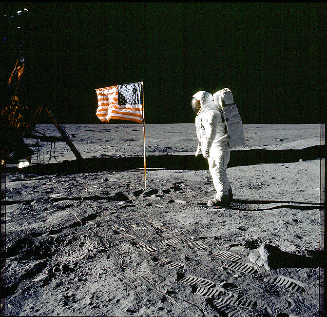Astronaut 'Buzz' Aldrin on the surface of the moon, standing next to the lunar capsule and the American flag.