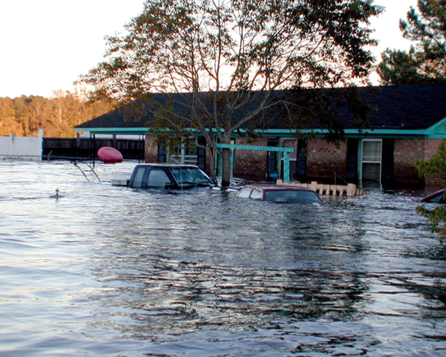 High floodwaters drown vehicles and houses.