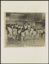 Image of the cover of a report on the Charlotte-Mecklenburg County School System, prepared by the NAACP, Charlotte Branch, 1972-1973. Image shows students playing basketball in a school gynnasium.