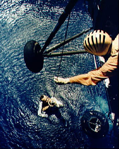 Astronaut Alan Shepard  hoisted from water by rescue team on a helicopter.