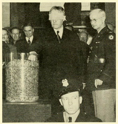 Photograph of Col. John D. Langston (right) with U.S. Secretary of War Henry Stimson (left).  Stimson is drawing a capsule in the selective service lottery on March 17, 1942.  From the March 1942 issue of <i>Selective Service</i>, page 1, published by the National Headquarters, Selective Service System, Washington, D.C. Presented on Archive.org. 