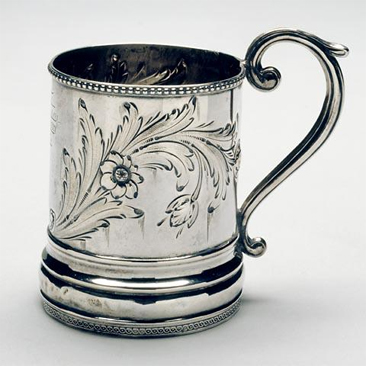 Photograph of sterling silver mug made by Traugott Leinbach, circa 1861-1865, showing floral repousse and engraved cartouche. Used by John Lawson Wrenn.  Item H.1933.4.1 from the collections of the North Carolina Museum of History.  Used courtesy of the North Carolina Department of Cultural Resources. 