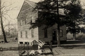 A 1911 photograph of the White Hart Lodge with Joseph Montfort's grave in front, draped with flags. Image from the North Carolina Museum of History.