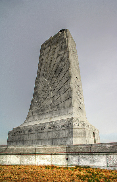 A large monolith sits on a grassy area.