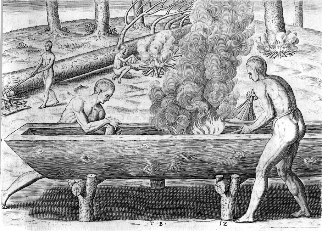 Two people carving a canoe. They are wearing loin cloths and are muscular. A fire is contained inside the canoe as other people chop wood in the background.