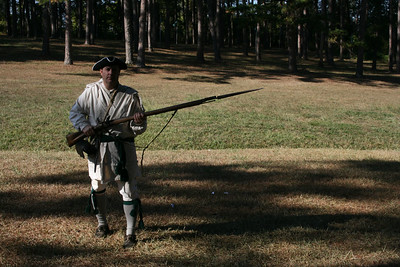 Regulator re-enactor with musket and bayonet standing in a large field. 