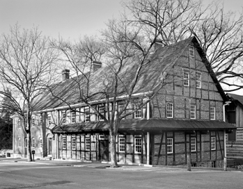 A brick house, with strong wooden braces and windows spread throughout. Black and white photos.