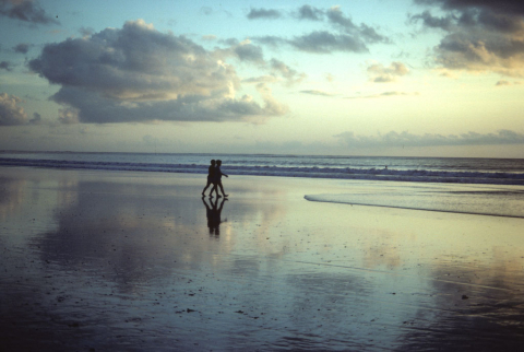 Silhouette of couple walking on Kuta Beach at sunset