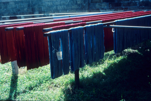 Blue and red dyed threads hang outside to dry at a Balinese weaving factory