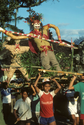 Young boys carry bamboo poles with soldier figures at Independence Day parade