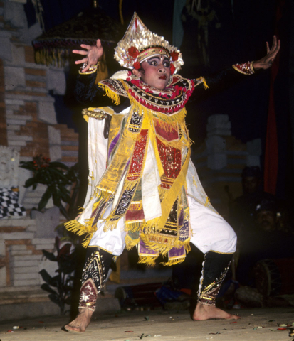 Boy stands with outstretched arms and fingers in Balinese warrior dance