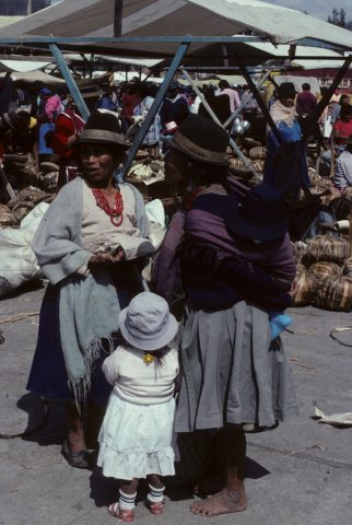 Two women and a child converse in the Saquisilí market