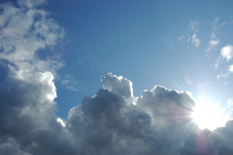 The sun breaks through clouds in a blue sky