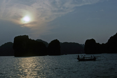 Evening view of fishing boat and small rocky islands in Halong Bay