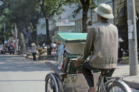 Rear view of a bicycle rickshaw transporting a passenger in downtown Hanoi.