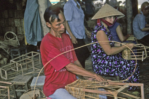 A man and a woman weave baskets in a handicraft factory near Dalat