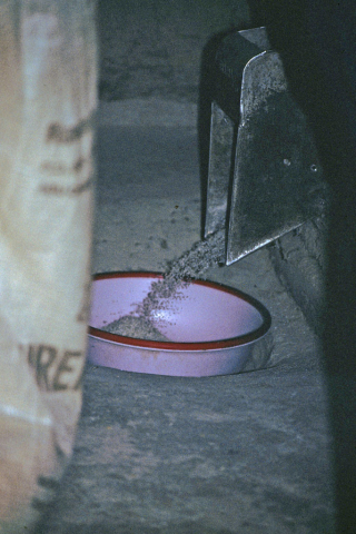 Threshing machine ejects rice into basin at mill near Mai Chau