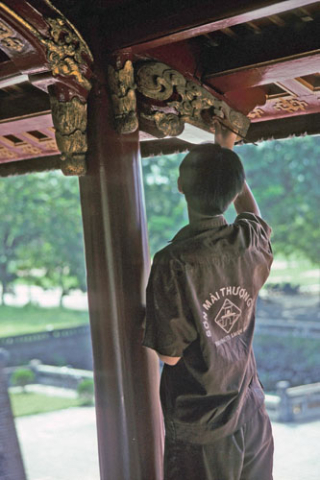 Man working for UNESCO paints carving on an Imperial City building at Hue