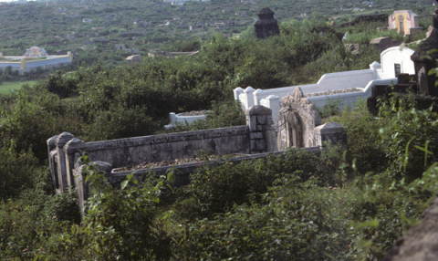 Older stone and newly painted white walled graves on hillside at Hue