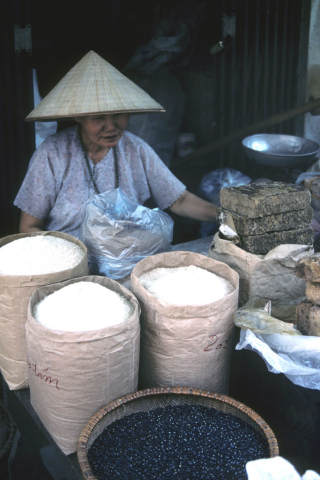 A woman sells rice from large bags at a Hanoi outdoor market