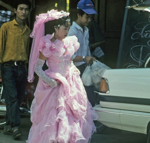 Bride walks through street in lacy pink wedding dress and high gloves at Mytho