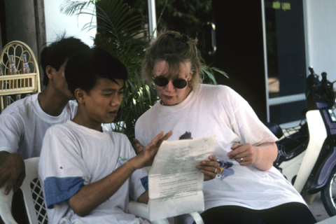 Two school boys ask a woman tourist in Hue to help them with English homework