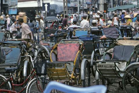 Bicycle rickshaws parked in busy Chinatown street of Ho Chi Minh City