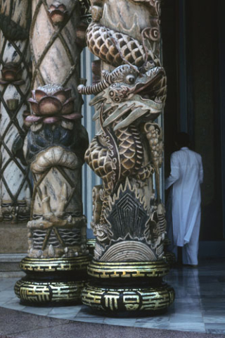 Carved columns and robed worshipper on veranda of Cao Dai temple at Tay Ninh