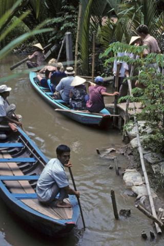 Two small passenger boats are poled in the shallow Mekong waters near Mytho