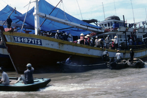 Large ship filled with passengers and four small motorboats in Mekong at Mytho