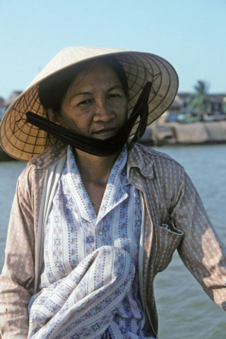 Portrait of woman in sunhat with chin strap and pajamas in boat at Hoi An