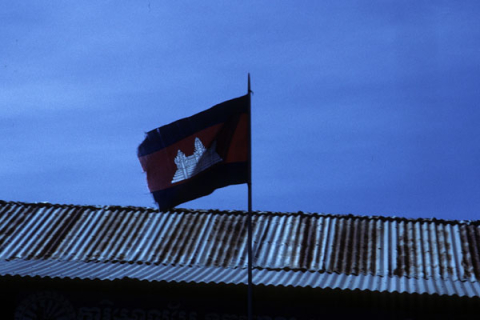 Cambodian flag flies above metal roof of building near Siem Reap