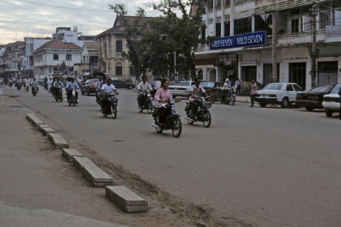 Phnom Penh downtown street with motorcycle traffic and buildings in background